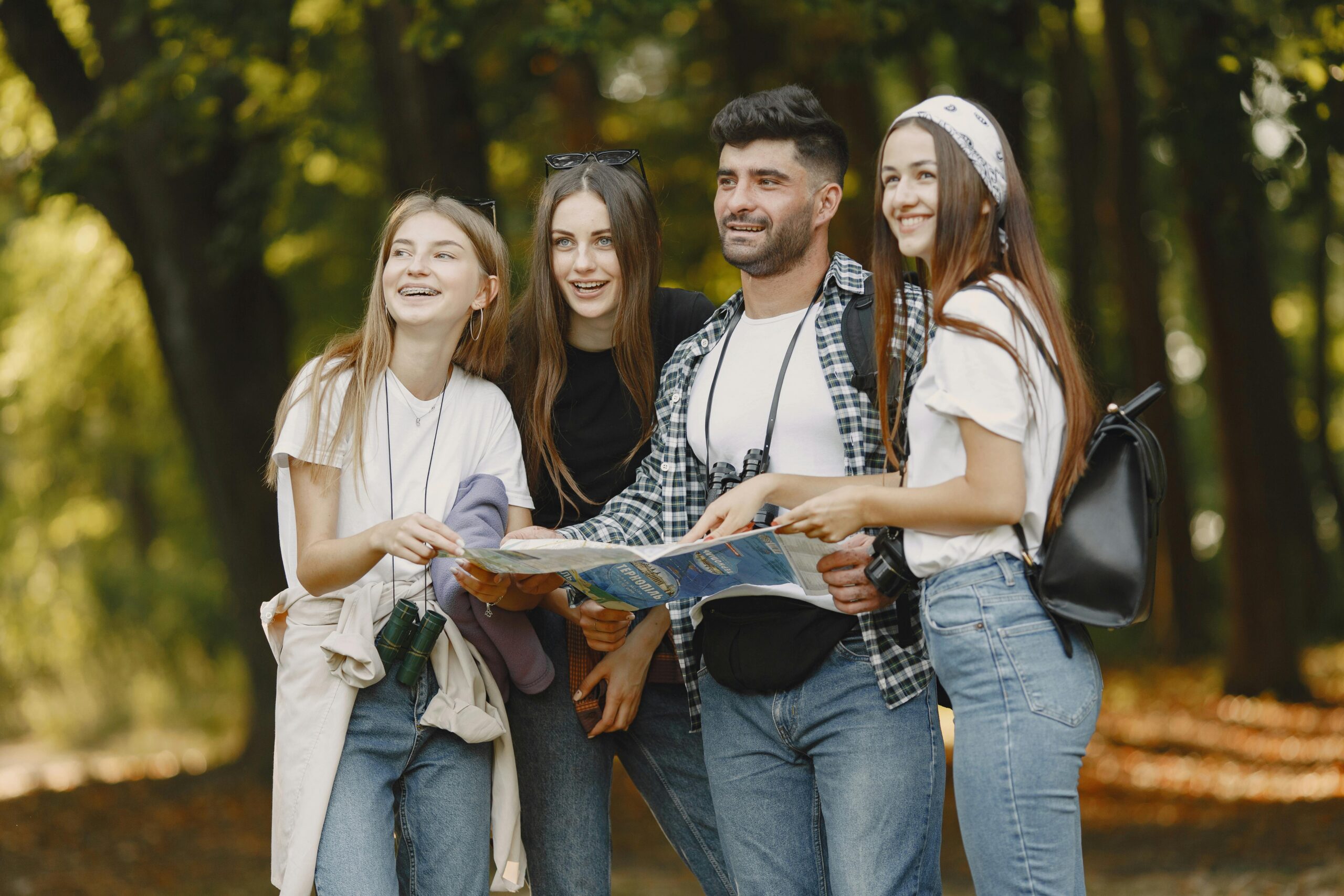 Group of friends in a park using a map to explore, enjoying a sunny day.